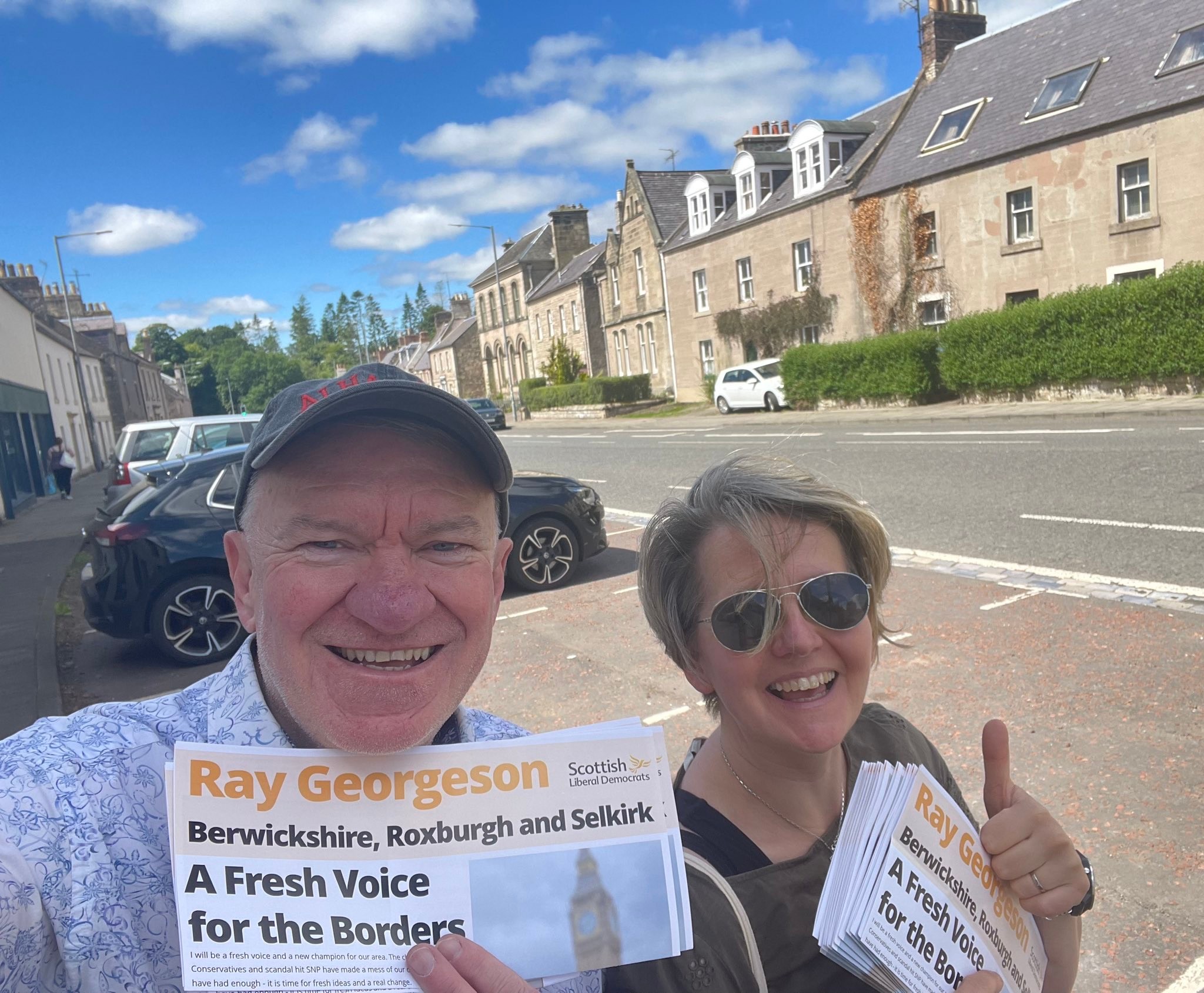 A photo of Ray and his wife holding a newspaper with Rays name on it